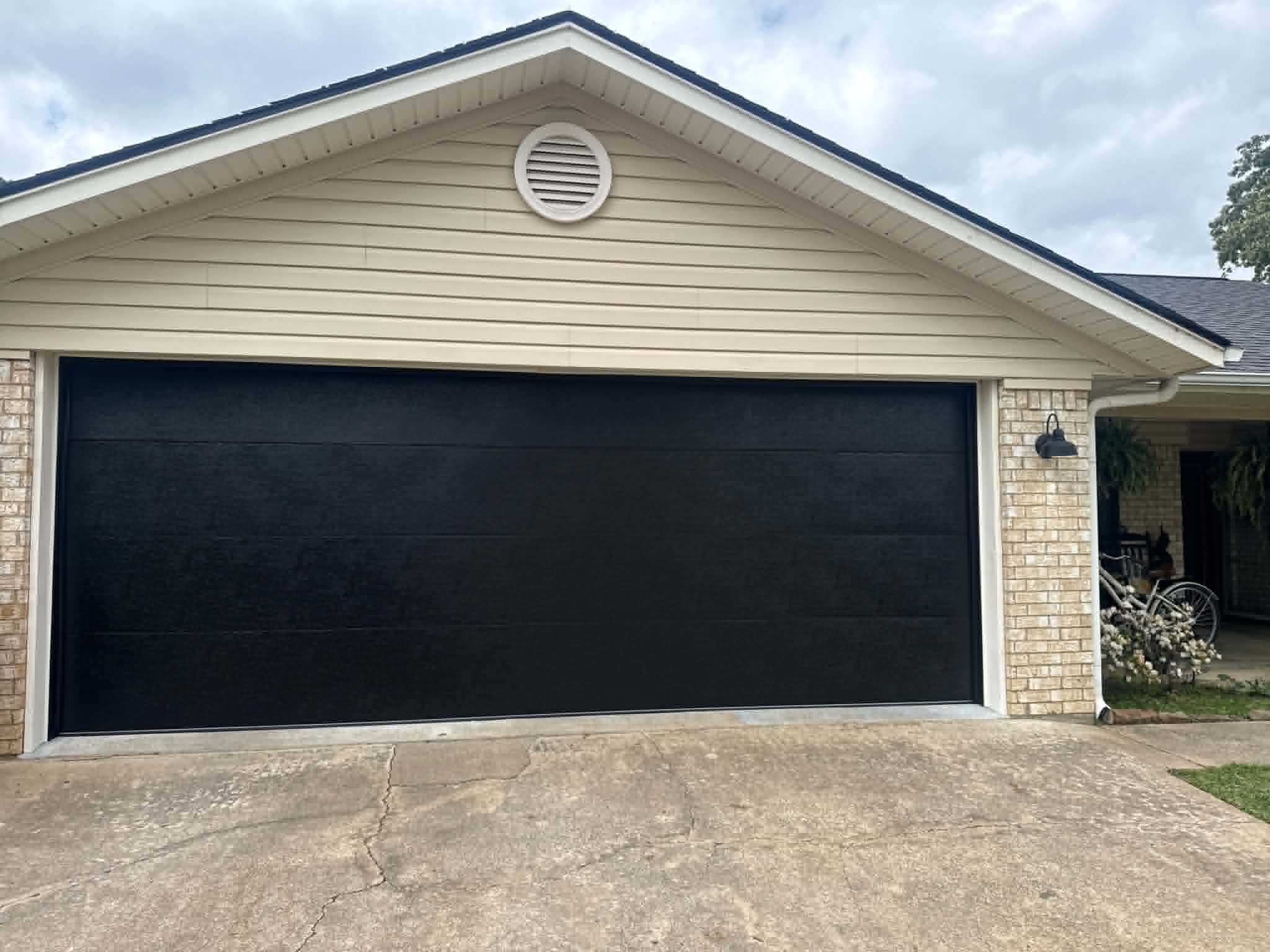 A new black garage door installed on a beige East Texas home